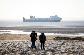Πολίτες περπατούν σε ακροθαλασσιά όπου λόγω κλιματικής κρίσης έχει πέσει η στάθμη