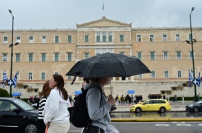 Πολίτες με ομπρέλα προστατεύονται από τη βροχή στο κέντρο της Αθήνας
