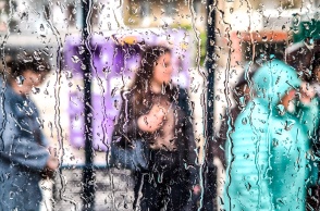 Πολίτες φαίνονται πίσω από βρεγμένο τζάμι