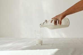 Ποτήρι με γάλα και μπουκάλι με γάλα σε λευκό φόντο