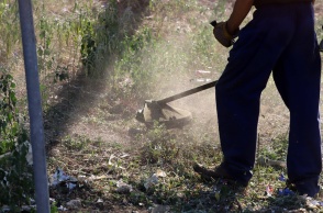 Άτομο καθαρίζει οικόπεδο από τα χορτάρια
