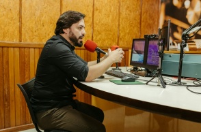 Άτομο σε στούντιο μπροστά από δύο μικρόφωνα