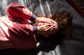 Κορίτσι που κρύβει το πρόσωπό του ενώ είναι ξαπλωμένο σε κρεβάτι