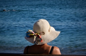 Γυναίκα με καπέλο κάθεται σε παγκάκι εν μέσω καύσωνα