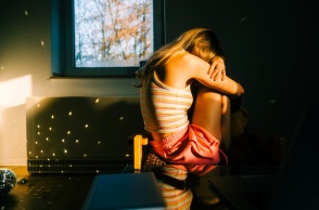 Γυναίκα κρύβει το πρόσωπό της και έχει στάσει σώματος αντίθετη από τον φωτογραφικό φακό