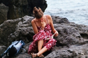 Κορίτσι που διαβάζει στην παραλία