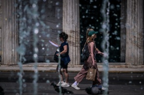 Πολίτες περπατούν πίσω από σιντριβάνι