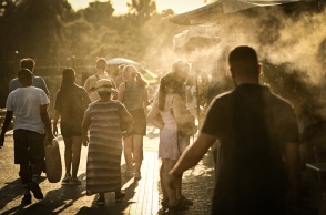 Πολίτες περπατούν υπό υψηλές θερμοκρασίες δίπλα σε σύστημα που βράζει σταγόνες νερού για δροσιά