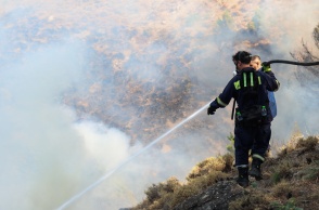 Πυροσβέστης με τη μάνικα ανά χείρας επιχειρεί για την κατάσβεσης φωτιάς