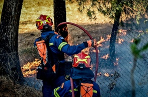 Πυροσβέστες με τις μάνικες επιχειρούν για την κατάσβεση φωτιάς