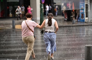 Βροχές και πολίτες που περπατούν στον δρόμο υπό βροχή