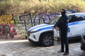 Αστυνομικός με την εξάρτισή του δίπλα από περιπολικό