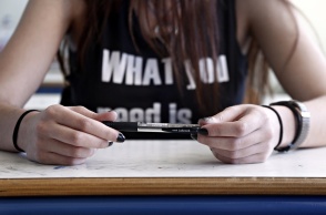 Μαθήτρια κρατά στυλό ενώ κάθεται στο θρανίο της