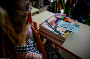 Μαθήτρια κάθεται στη θέση της έχοντας τα βιβλία της μπροστά της πάνω στο θρανίο και σημειώματα για καλή σχολική χρονιά