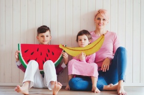 Μητέρα με παιδιά και μεγάλα χαρτόνια με φρούτα