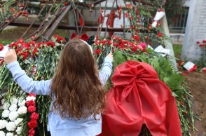 Παιδί αφήνει ένα κόκκινο γαρύφαλλο στο μνημείο για την εξέγρεση του Πολυτεχνείου