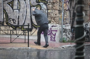 Άτομο σηκώνει το κουστούμι για να προστατευτεί από τη βροχόπτωση
