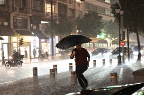 Πολίτης με ομπρέλα εν μέσω καταιγίδες και πλημμυρισμένων δρόμων