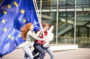 Νεαρά κορίτσια που κρατούν τρέχοντας τη σημαίατης ΕΕ