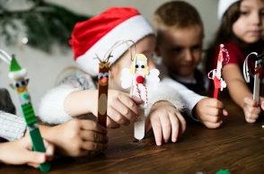 Παιδιά με χριστουγεννιάτικα σκουφιά κρατούν χριστουγεννιάτικα στολίδια