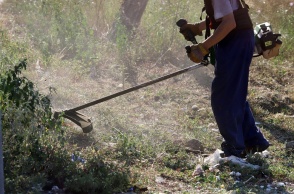 Άτομο με χορτοκοπτικό καθαρίζει οικόπεδο