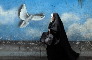 Γυναίκα στην Τεχεράνη, την πρωτεύουσα του Ιράν, περνά μπροστά από mural που δείχνει ένα περιστέρι να πετά