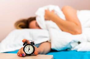 Γυναίκα στο κρεβάτι κλείνει το ξυπνητήρι