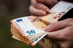 Άνδρας μετρά χαρτονομίσματα του ευρώ