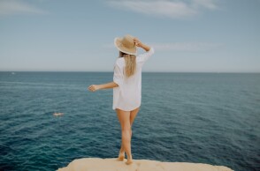 Γυναίκα με καπέλο μπροστά στη θάλασσα