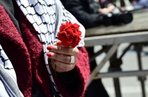 Γυναίκα κρατά κόκκινο γαρύφαλλο για την Πρωτομαγιά