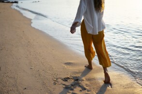 Γυναίκα περπατά ξυπόλυτη στην παραλία