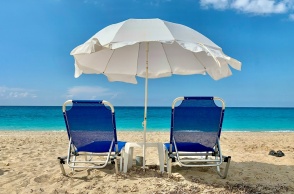 Παραλία στη Λευκάδα με δύο ξαπλώστρες και μία ομπρέλα καρφωμένη στην άμμο