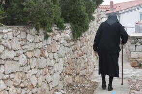 Ηλικιωμένη με μπαστούνι περπατά σε σοκάκι