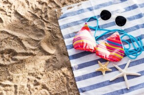 Μαγιό, γυαλιά ηλίου και αστερίες σε πετσέτα θαλάσσης στην άμμο