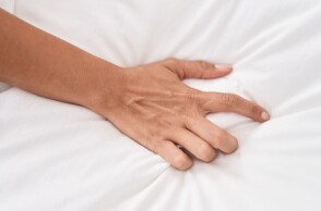 Χέρι πιάνει σεντόνι σε κρεβάτι