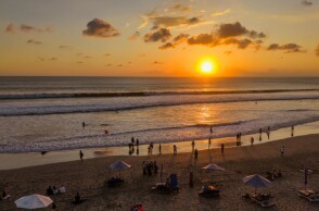 Λουόμενοι σε παραλία με φόντο το ηλιοβασίλεμα