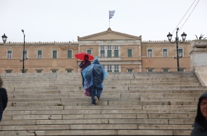 Πολίτες με ομπρέλα και αδιάβροχο μπροστά στη Βουλή