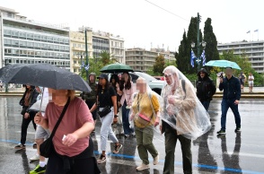 Πολίτες με ομπρέλες ανά χείρας προστατεύονται από τη βροχή