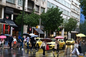 Πολίτες με ομπρέλα σε δρόμο της Αττικής