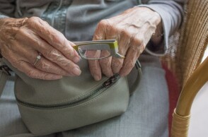 Ηλικιωμένη κρατά γυαλιά πρεσβυωπίας και τσάντα στα χέρια