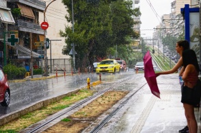 Βροχή και κοπέλες που κλείνουν την ομπρέλα τους σε στάση τραμ