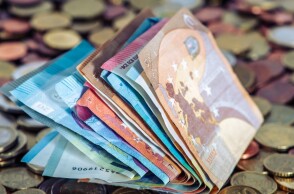 Διπλωμένα χαρτονομίσματα και κέρματα του ευρώ