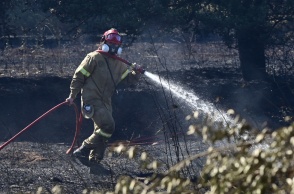 Πυροσβέστης με τη μάνικα ανά χείρας επιχειρεί για την κατάσβεσης φωτιάς