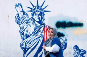 Γυναίκα περνά μπροστά από mural στην Τεχεράνη  με το άγαλμα της Ελευθερίας