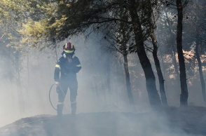 Πυροσβέστης με μάνικα εν μέσω καπνών