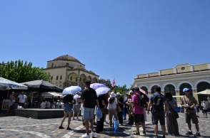 Πολίτες με ομπρέλες και καπέλα υπό καυτό ήλιο στην πλατεία Μοναστηρακίου