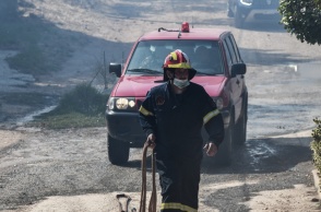 Πυροσβέστης μπροστά από όχημα με τη μάνικα ανά χείρας