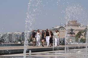 Πολίτες περπατούν πίσω από το σιντριβάνι στην παραλία της Θεσσαλονίκης