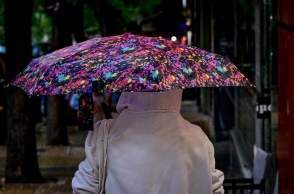 Γυναίκα προστατεύεται με ομπρέλα από τη βροχή