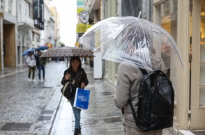 Πολίτες με ομπρέλες σε κεντρικό εμπορικό δρόμο